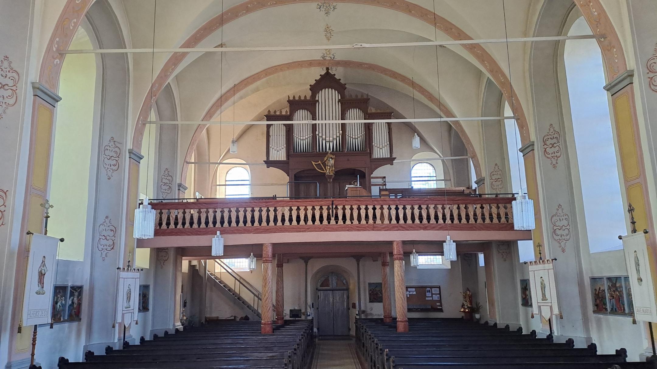 Blick vom Altarbereich zur Orgelempore der Kirche St. Kastor in Mörsdorf. Die historische Orgel, die Empore und die harmonische Architektur des Kirchenraums stehen im Mittelpunkt der Aufnahme.