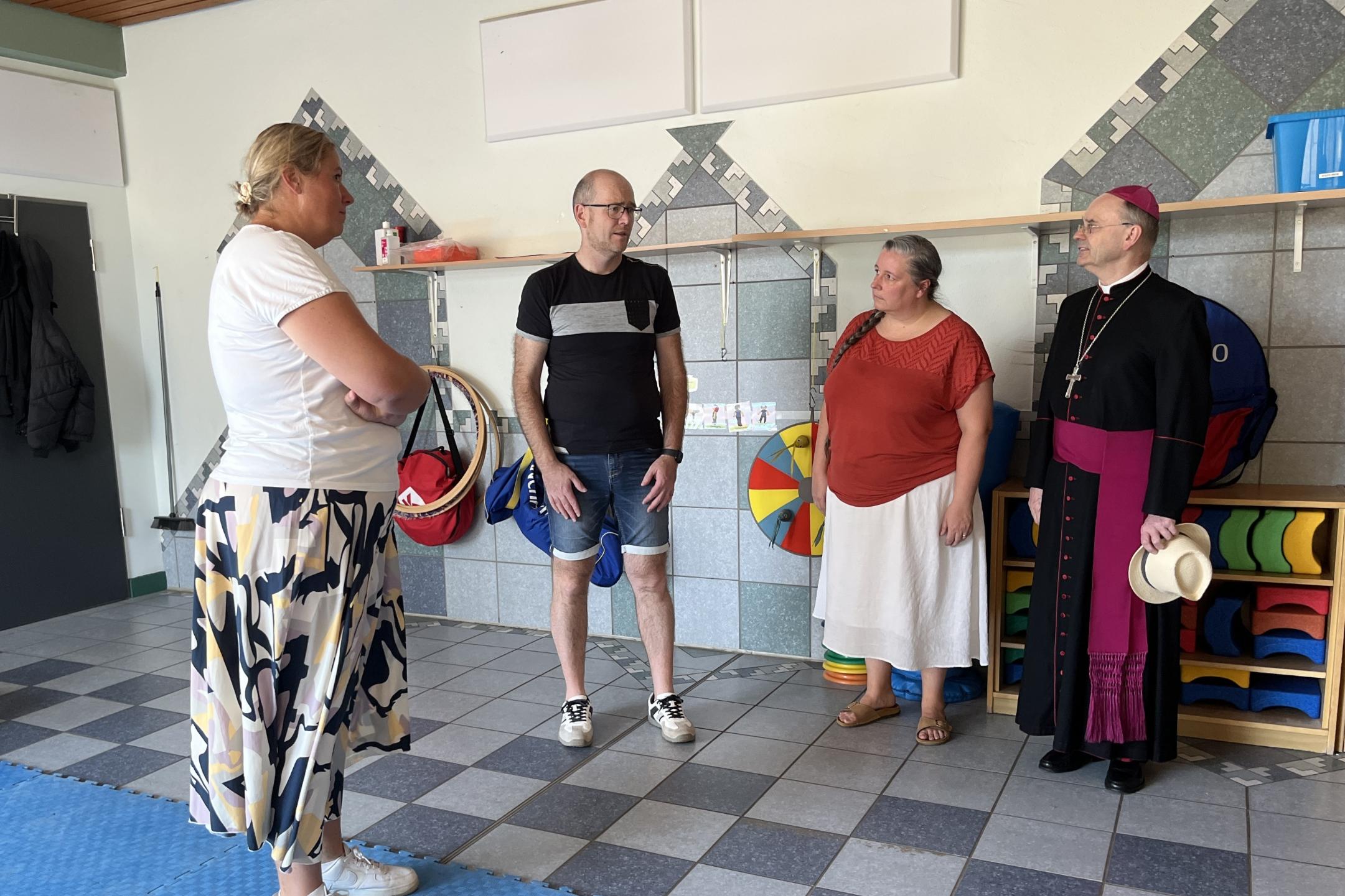 Weihbischof Brahm schaut sich gemeinsam mit (v. links) Erzieherin Stefanie Dix, Standortleiter Stefan Wendling und Pastoralreferentin Lisa Lorsbach den Toberaum an.